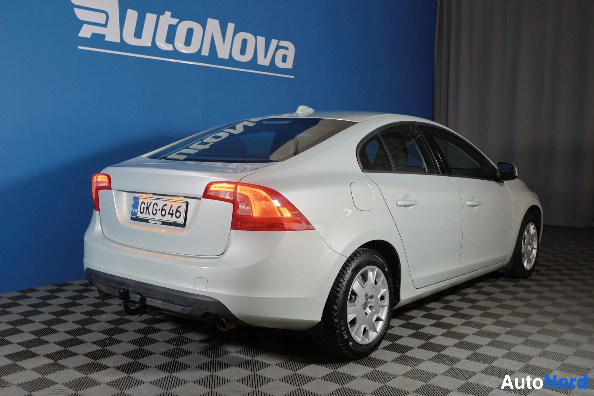 Takaviisto: Volvo S60 takaa kolme neljäsosaa kuvattuna, valkoinen väri, rekisteritunnus näkyvillä, LED-takavalot punaisina, alumiiniset navakuvut