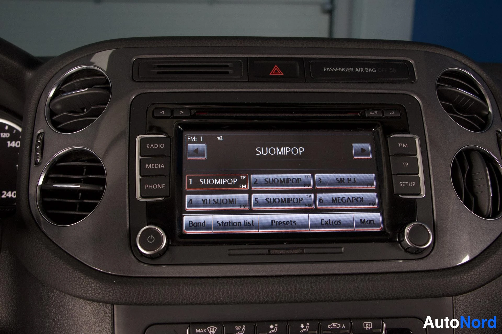 Ohjaamo: Kuva auton infotainment-järjestelmän näytöstä, joka näyttää radion taajuusvalinnan. Näytöllä on useita radioasemia, mukaan lukien "SUOMIPOP" ja "YLEISUOMI". Ilm