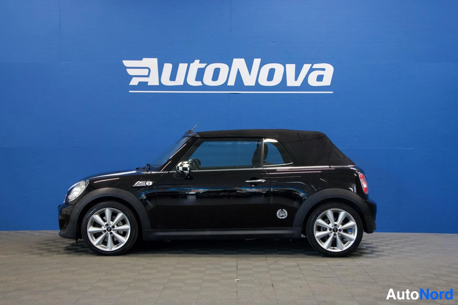 Sivulta: Musta Mini Cooper avoauto sivusta, suljettu katto, valkoiset vanteet, pituuskuva