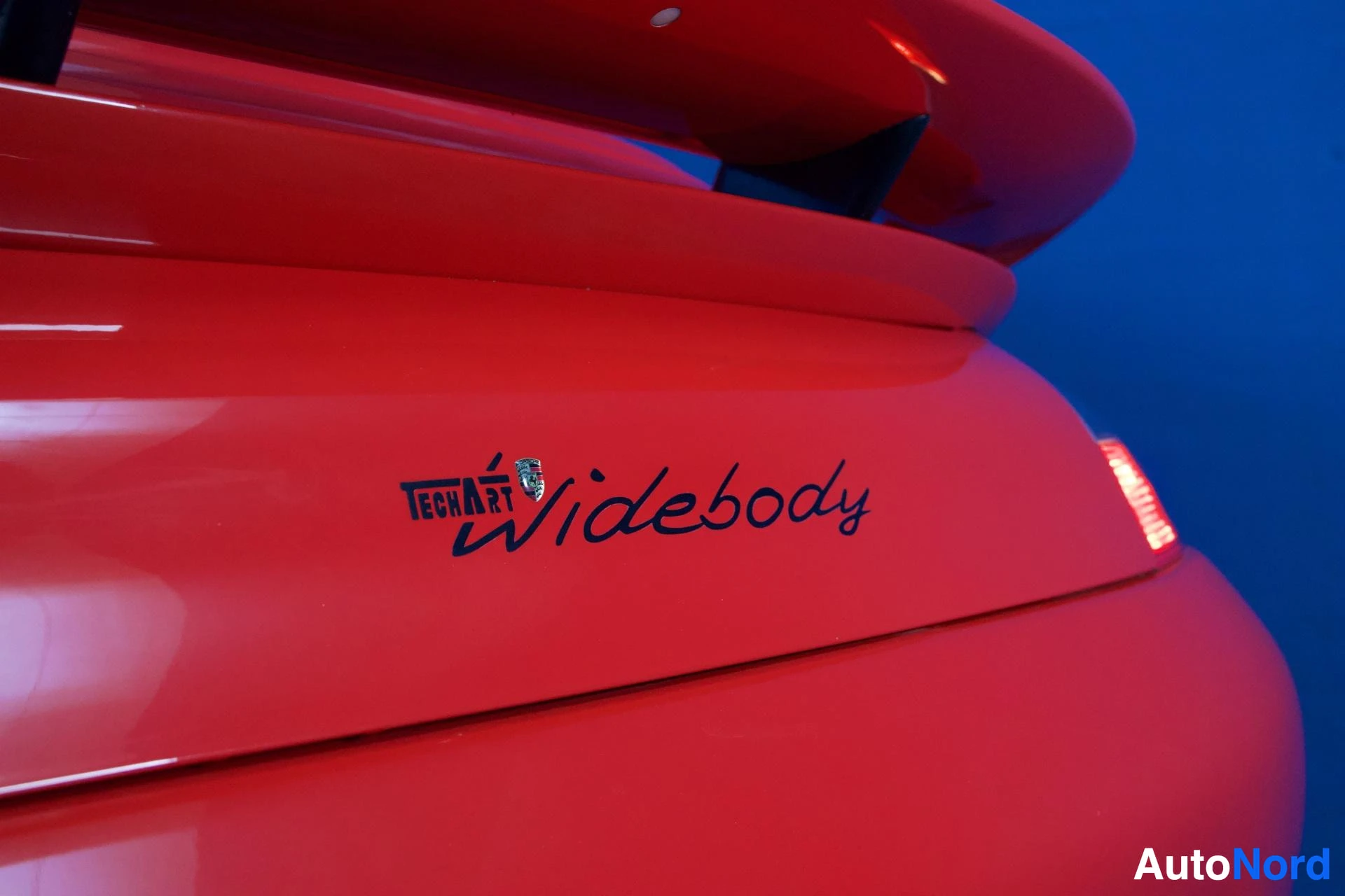 Yksityiskohta: Punaisen auton sivupaneeli, jossa näkyy musta teksti 'widebody' ja logo