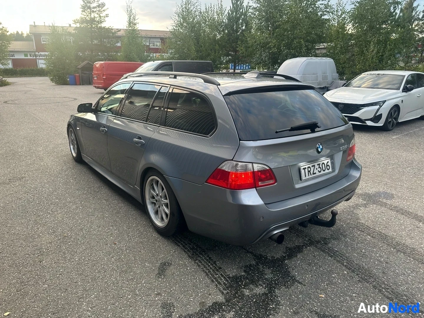 Takaviisto: Hopeanväriset BMW 535d maastoauto takanäkymästä oikealta, valkoiset alloying-pyörät ja punaiset takavalaistukseltä