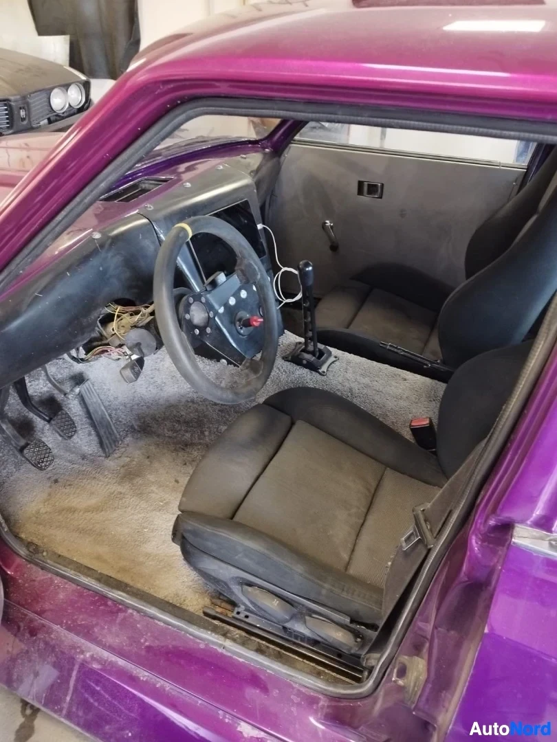 Ohjaamo: Magentanvärinen auto, ovi auki, näkyvissä ohjausratti, kojelauta ja tummanväriset istuimet sisäpuolelta