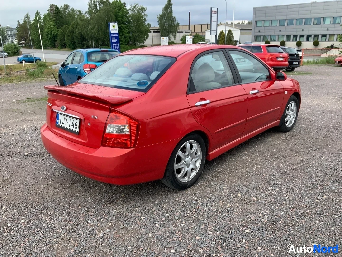 Takaviisto: Punainen Kia Cerato -sedan, sivusta takapuoli näkyvissä, rekisteritunnuksella IHI146