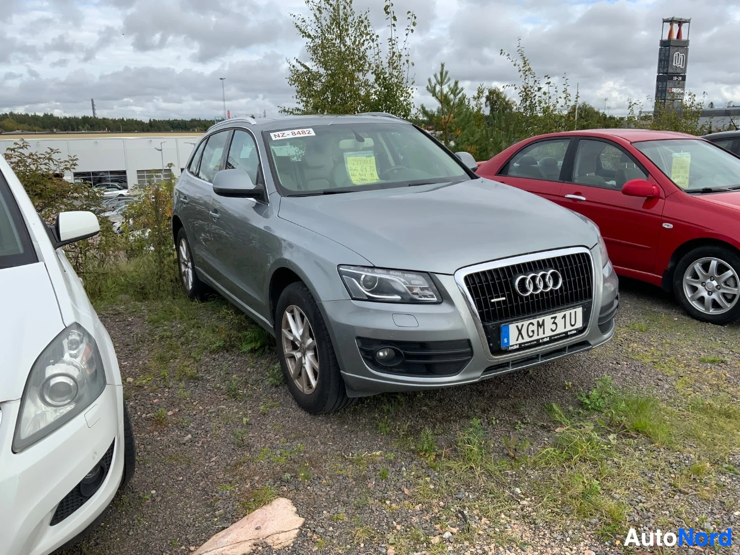Etuviisto, nokka oikealle: Harmaa Audi Q5 maastoauto pysäköitynä ulkona, auton keula ja oikea kylki näkyvissä. Rekisterikilpi näkyy selvästi.