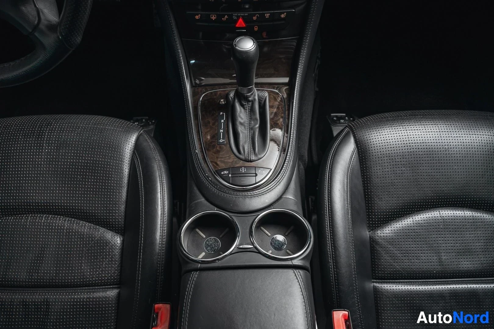 Yksityiskohta: Valkoinen Mercedes-Benz CLS 63 AMG, automaattivaihteiston valitsin, keskikonsoli ja mukitelineet