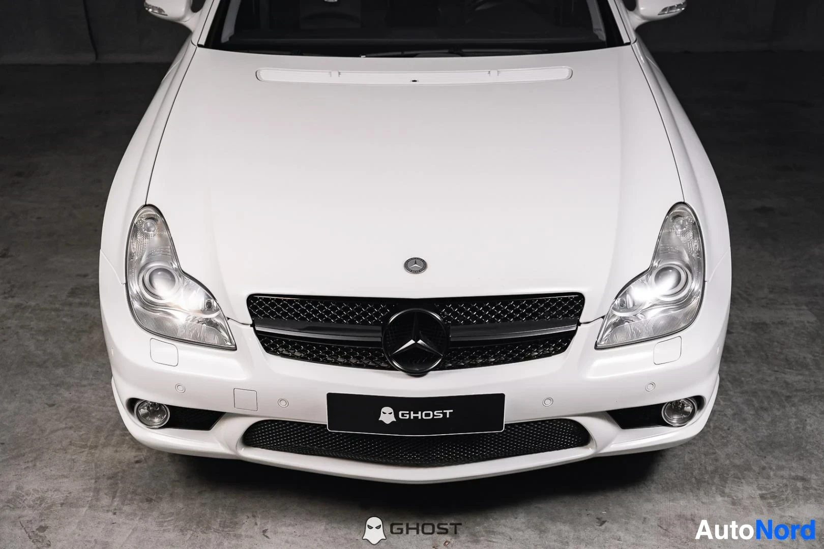 Edestä: Valkoinen Mercedes-Benz CLS 63 AMG, lähikuva keulasta, ajovalot ja etusäleikkö