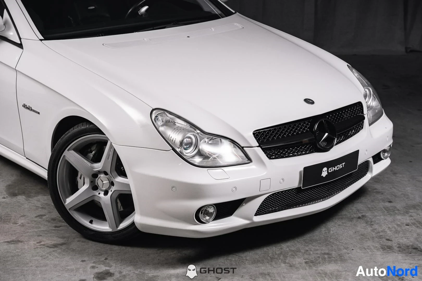 Etuviisto, nokka oikealle: Valkoinen Mercedes-Benz CLS 63 AMG, lähikuva keulasta ja hopeanvärisestä etuvanteesta