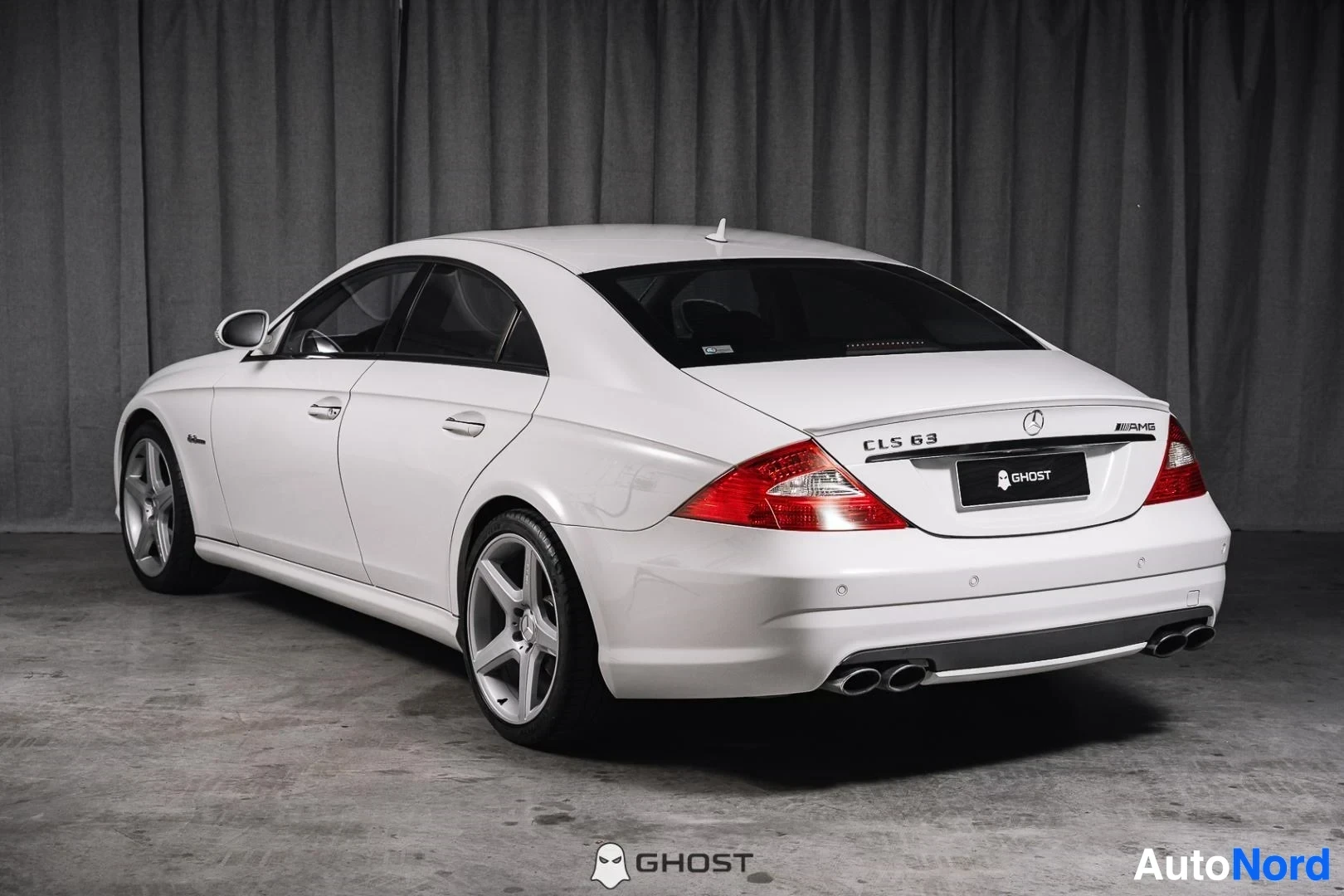 Takaviisto: Valkoinen Mercedes-Benz CLS 63 AMG, koko ajoneuvo näkyvissä sivusta ja takaa, studiotausta