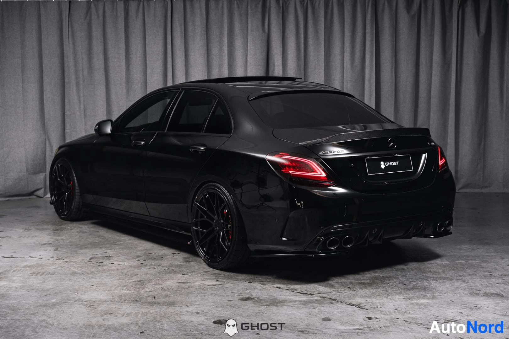 Takaviisto: Musta Mercedes-Benz C 43 AMG, koko ajoneuvo näkyvissä sivusta ja takaa, mustat vanteet, studiotausta