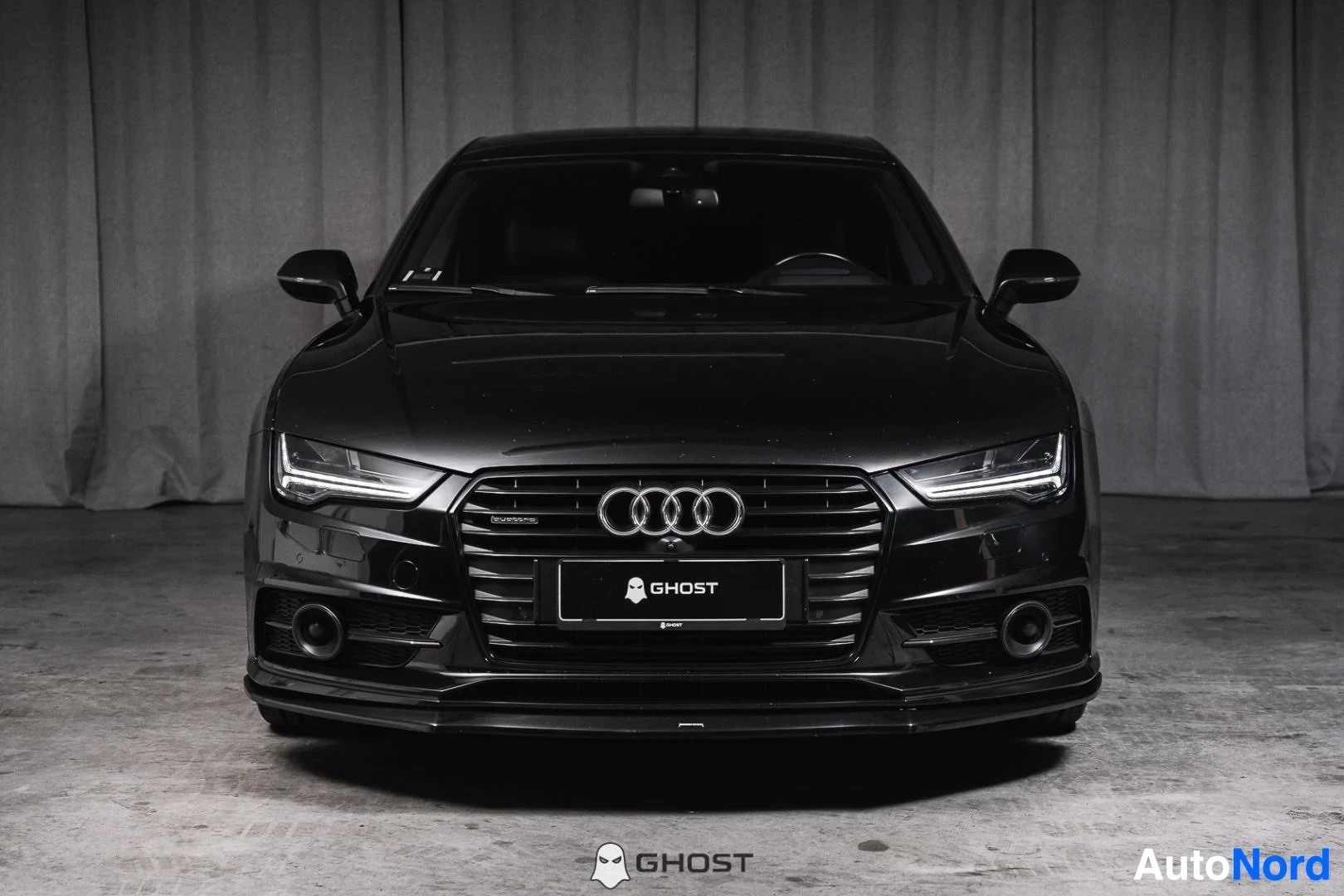 Edestä: Musta Audi A7, koko ajoneuvo näkyvissä, LED-ajovalot ja kromikehyksinen säleikkö, studiotausta