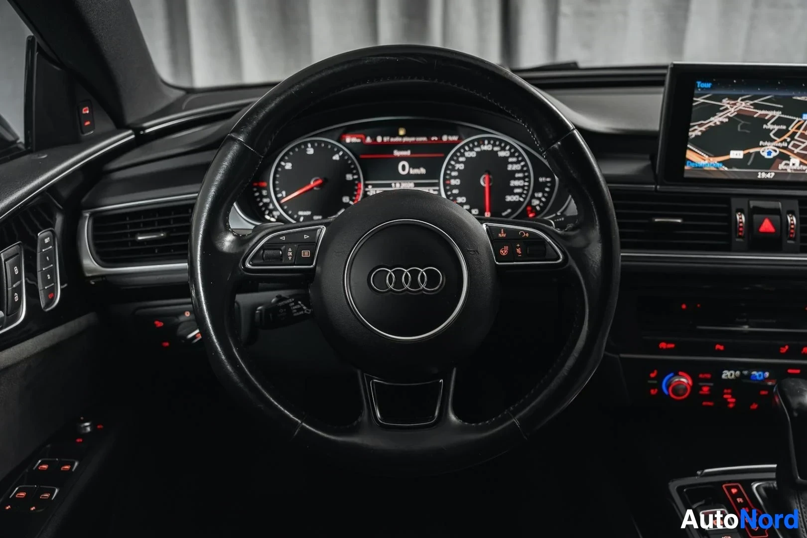 Ohjaamo: Musta Audi A7, ohjauspyörä ja mittaristo kuljettajan puolelta, keskinäyttö taustalla