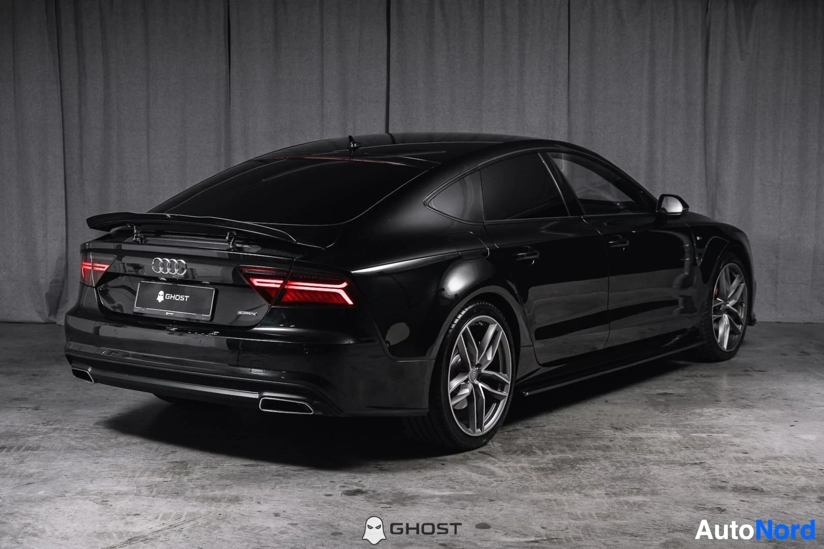 Takaviisto: Musta Audi A7, koko ajoneuvo näkyvissä, LED-takavalot ja takaspoileri, studiotausta