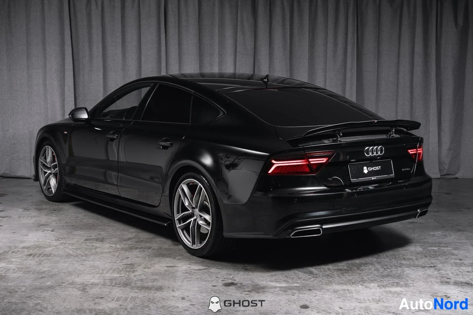 Takaviisto: Musta Audi A7, koko ajoneuvo näkyvissä, Sportback-takaosa ja harmaat vanteet, studiotausta