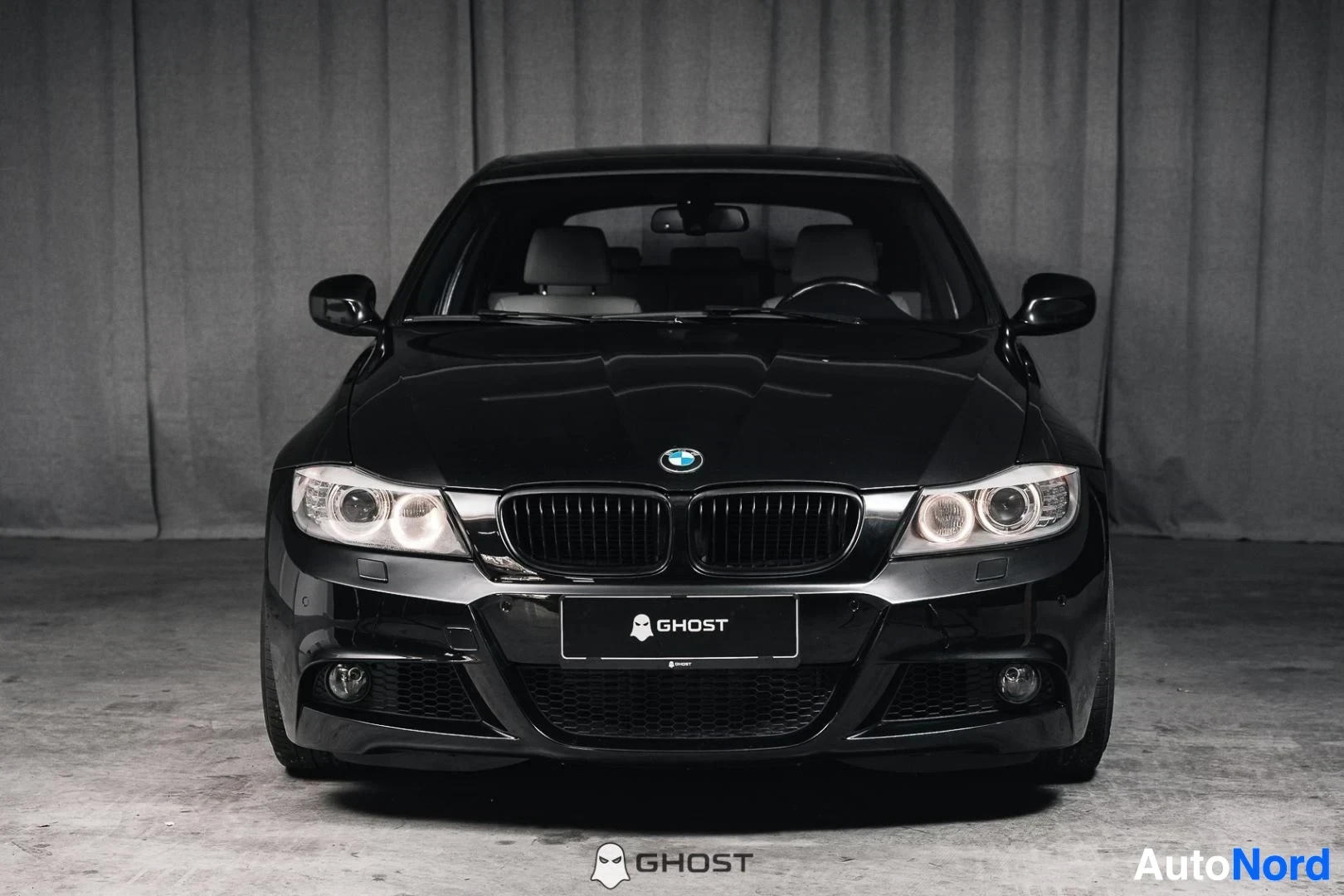 Edestä: Musta BMW 335i xDrive E91 Touring, koko ajoneuvo näkyvissä, M-Sport-etupuskuri ja xenon-ajovalot, studiotausta