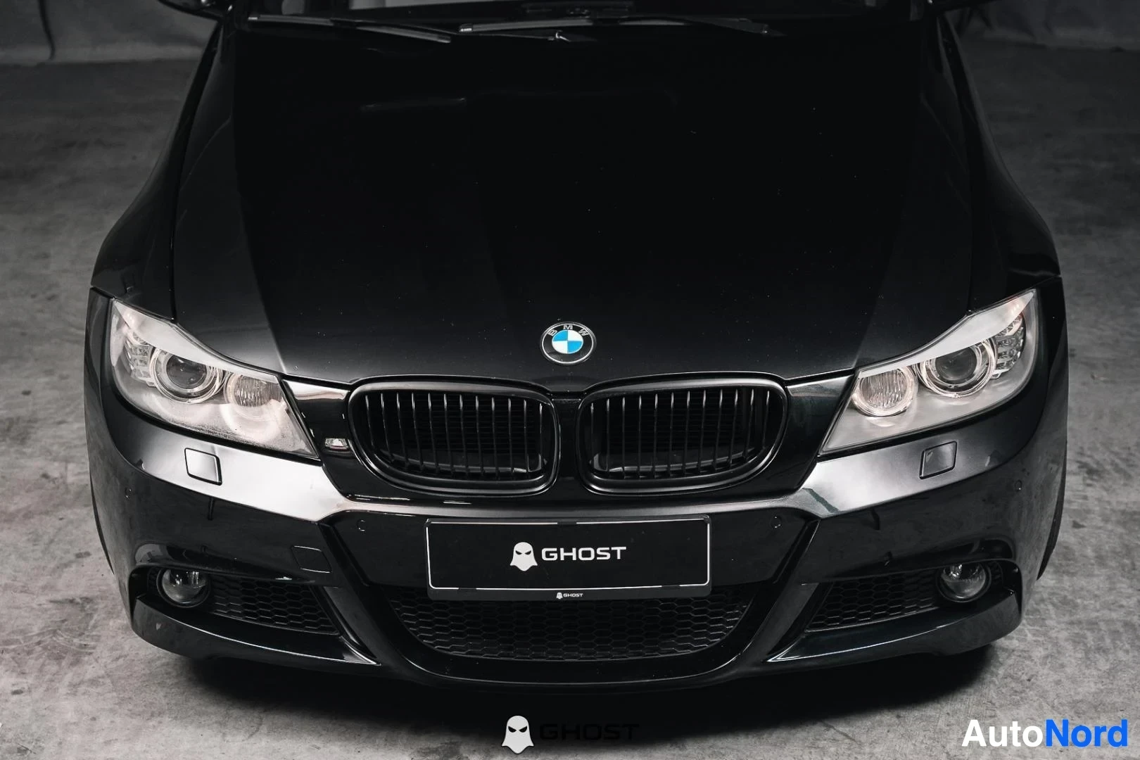 Edestä: Musta BMW 335i xDrive E91 Touring, lähikuva keulasta, munuaissäleikkö ja ajovalot
