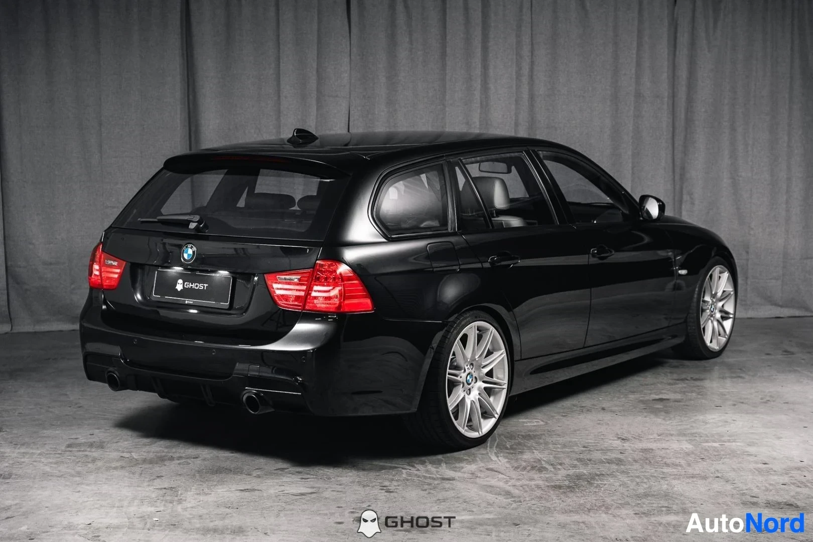 Takaviisto: Musta BMW 335i xDrive E91 Touring, koko ajoneuvo näkyvissä, farmarin takaosa ja kylki, studiotausta