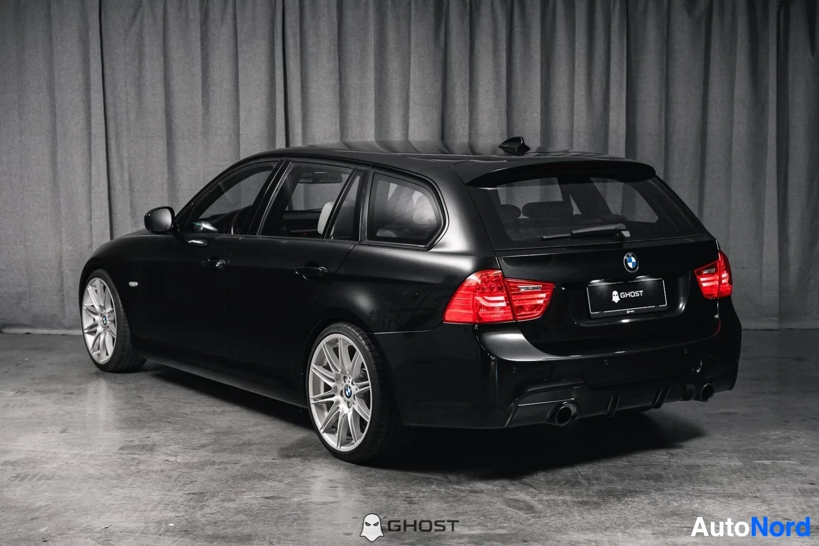 Takaviisto: Musta BMW 335i xDrive E91 Touring, koko ajoneuvo näkyvissä, takavalot ja kylki, studiotausta