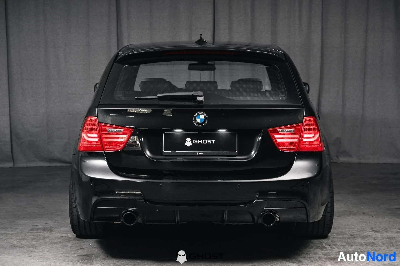 Takaa: Musta BMW 335i xDrive E91 Touring, koko ajoneuvo näkyvissä, takaluukku, LED-takavalot ja kaksoispakoputket