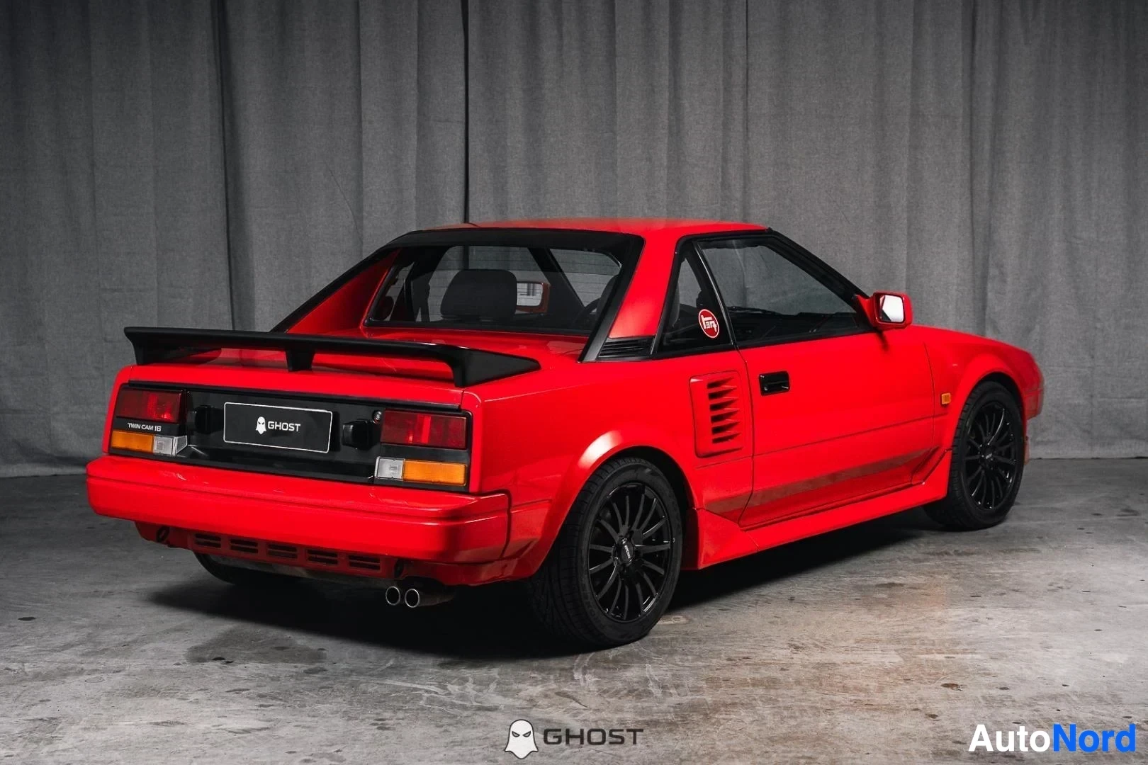 Takaviisto: Punainen Toyota MR2, koko ajoneuvo näkyvissä, takasiipi, studiotausta