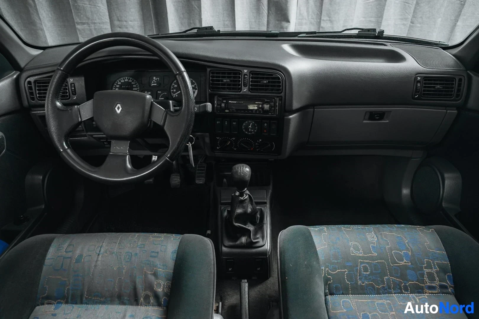 Ohjaamo: Tummansininen Renault 19, kojelauta, ohjauspyörä ja manuaalivaihteisto, kuvioidut kangasistuimet