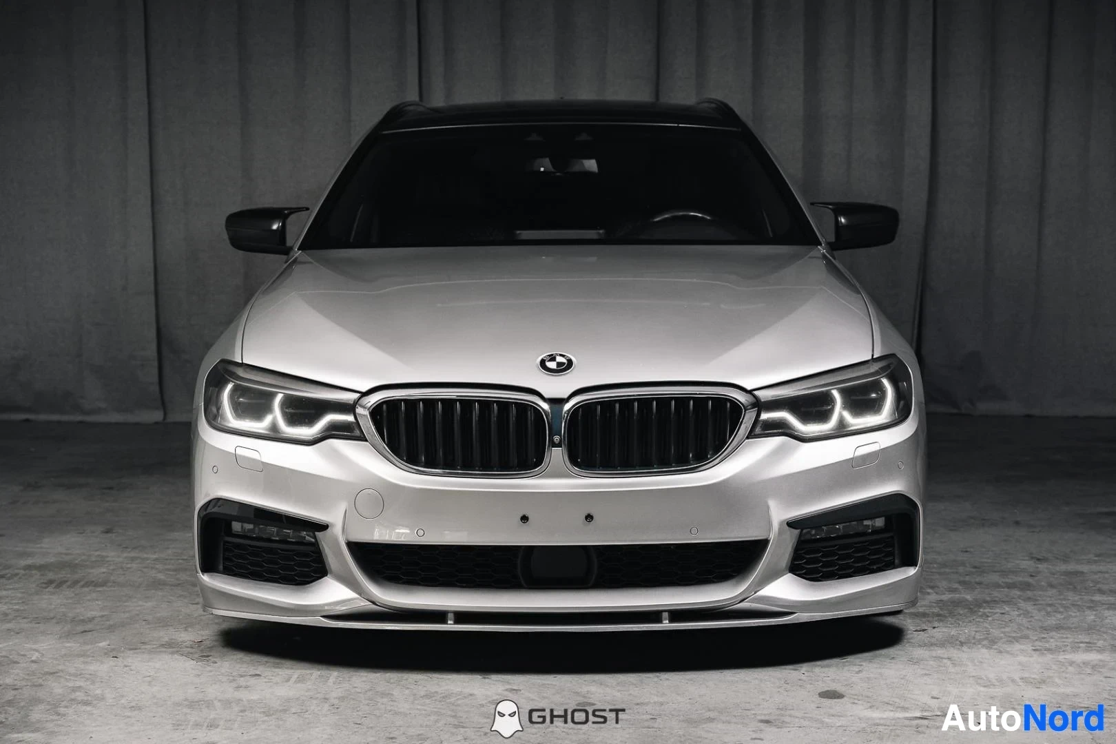 Edestä: Hopeanharmaa BMW 540i G31 xDrive Touring, koko ajoneuvo näkyvissä, LED-ajovalot ja M-Sport-etupuskuri, studiotausta