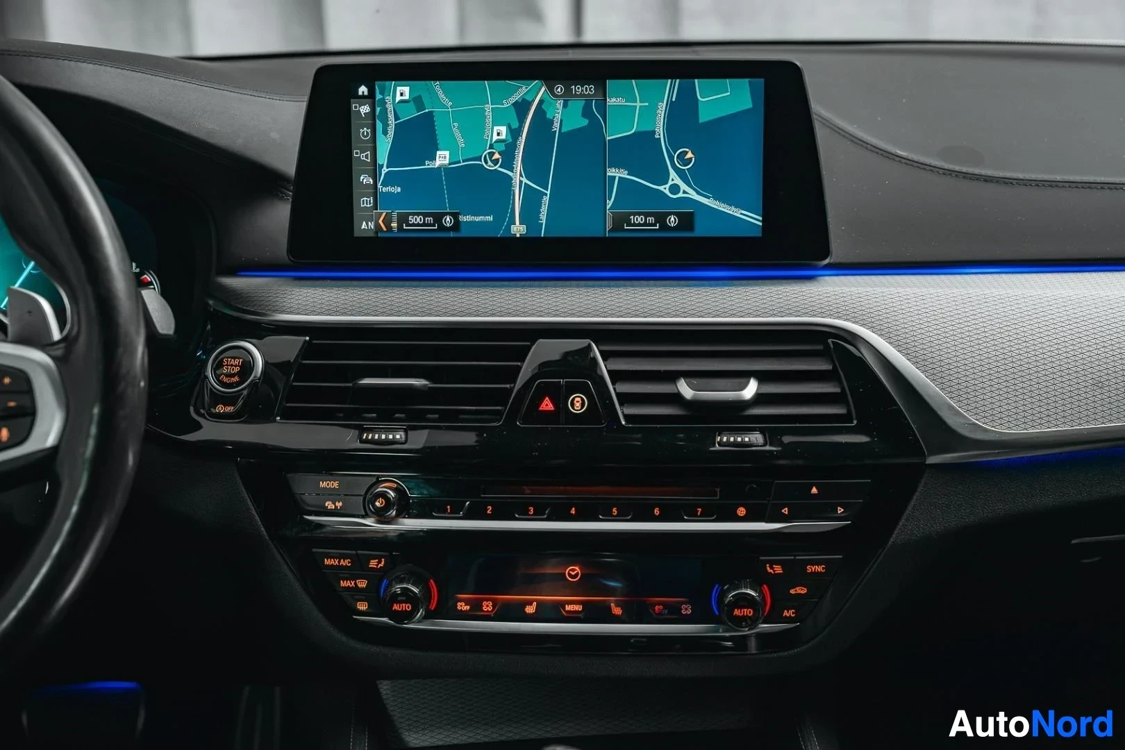 Yksityiskohta: Hopeanharmaa BMW 540i G31 xDrive Touring, keskinäyttö navigointinäkymällä, radio ja ilmastoinnin säätimet