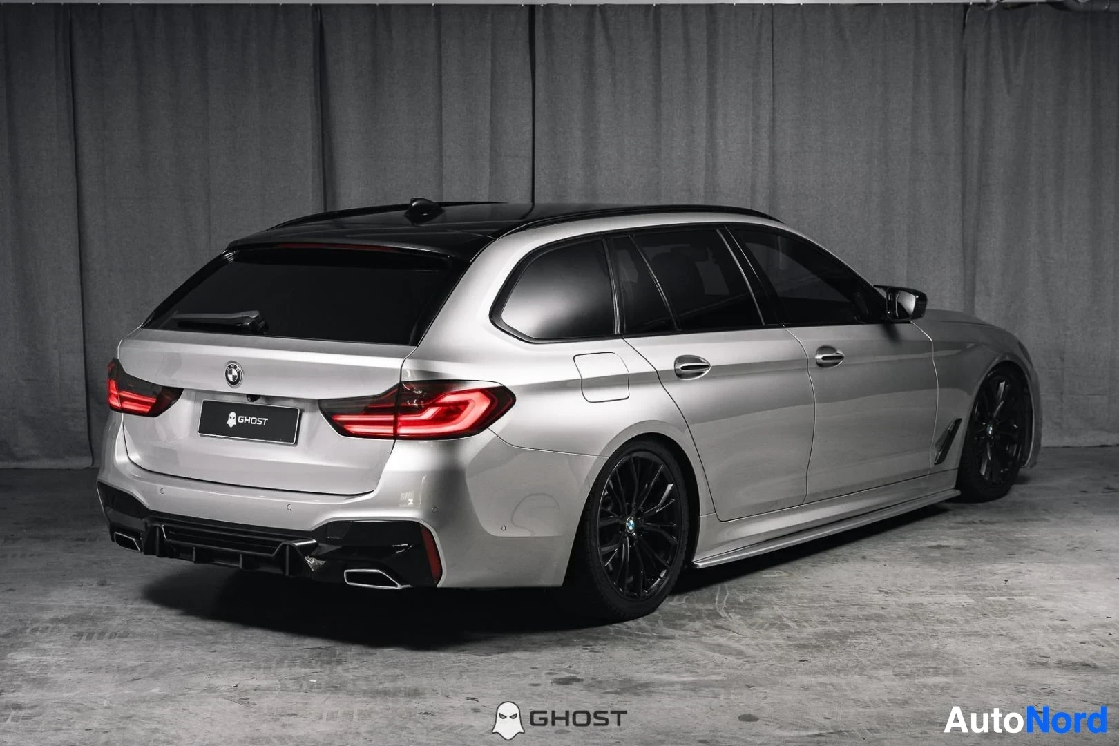 Takaviisto: Hopeanharmaa BMW 540i G31 xDrive Touring, koko ajoneuvo näkyvissä, farmarin takaosa ja kylki, studiotausta