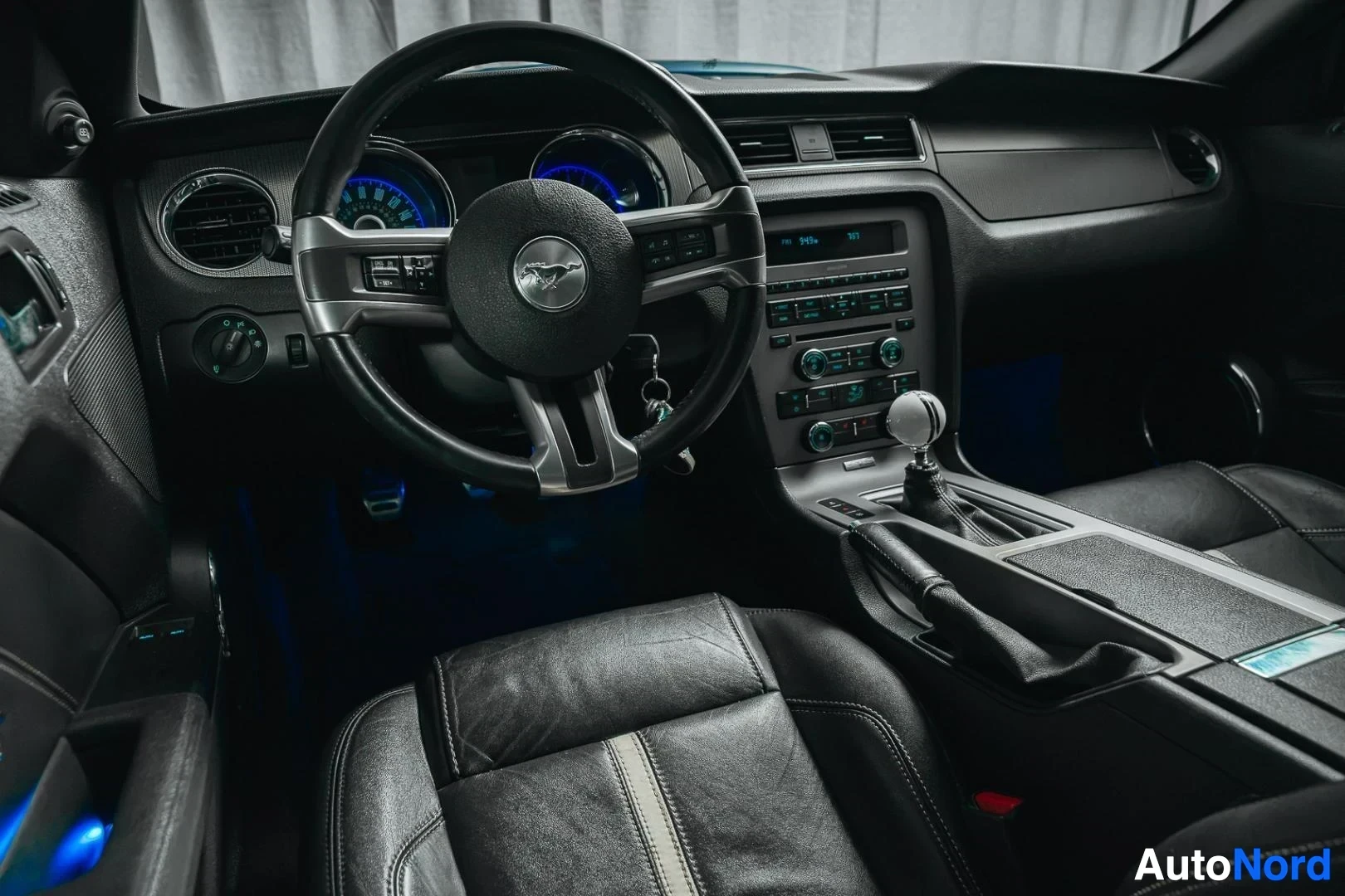 Ohjaamo: Sininen Ford Mustang GT, kojelauta kuljettajan puolelta, ohjauspyörä, keskikonsoli ja nahkaistuimet