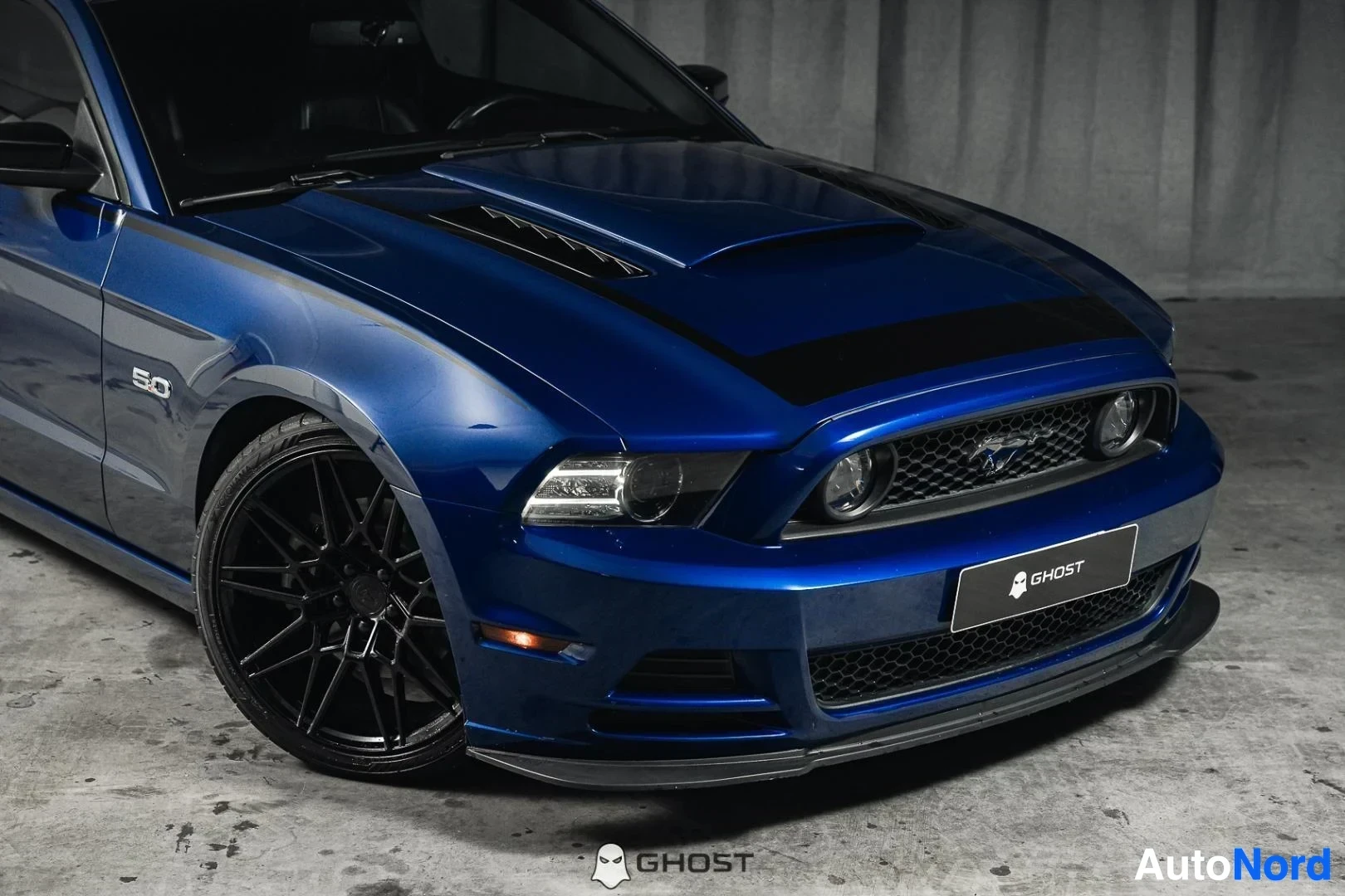 Etuviisto, nokka oikealle: Sininen Ford Mustang GT, lähikuva keulasta ja mustasta etuvanteesta