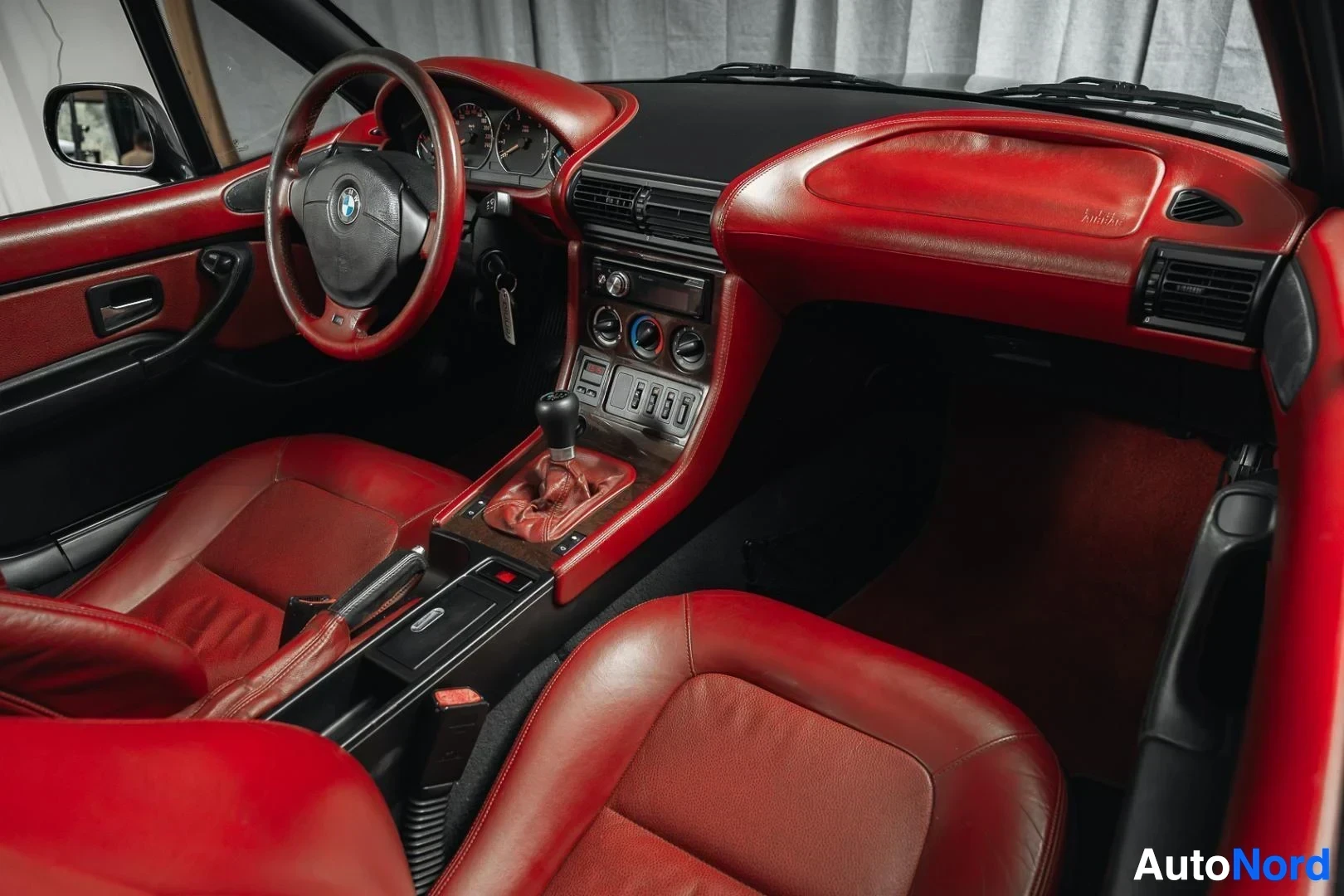 Ohjaamo: Musta BMW Z3 Roadster, kojelauta ja etuistuimet matkustajan puolelta kuvattuna, punainen nahkaverhoilu