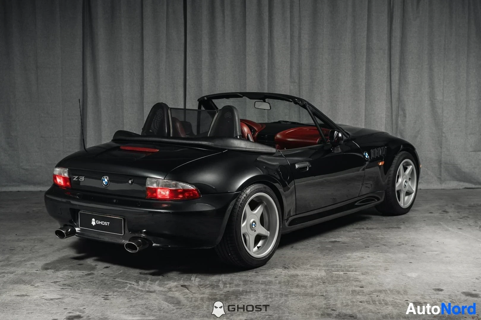 Takaviisto: Musta BMW Z3 Roadster, koko ajoneuvo näkyvissä, avoauton takaosa ja kylki, studiotausta