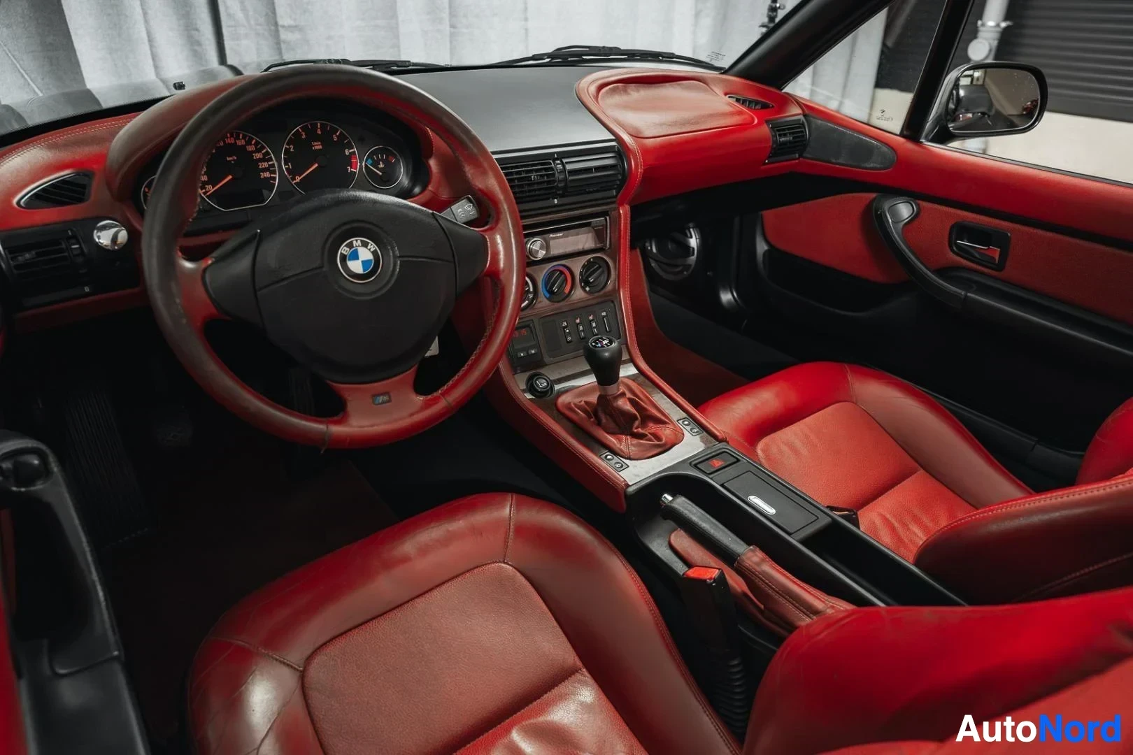 Ohjaamo: Musta BMW Z3 Roadster, kojelauta ja ohjauspyörä kuljettajan puolelta kuvattuna, punainen nahkaverhoilu