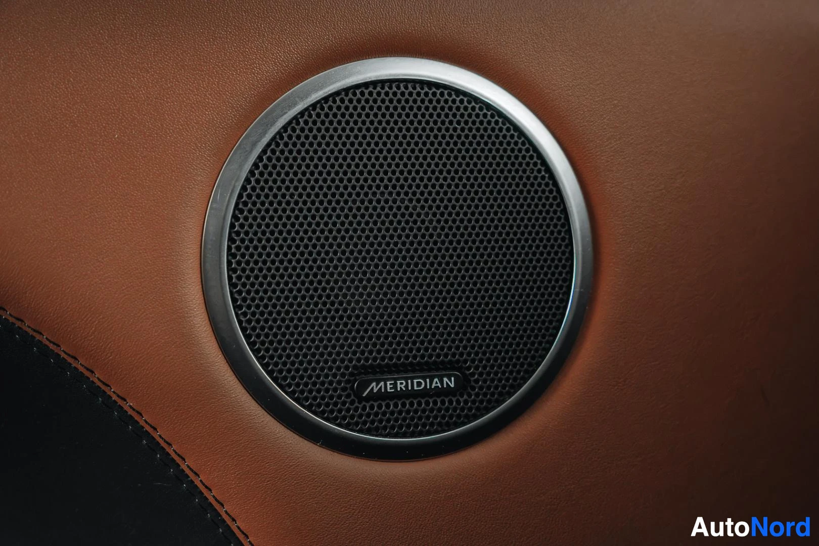 Yksityiskohta: Musta Land Rover Range Rover Sport, Meridian-kaiutin oven ruskeassa nahkaverhoilussa