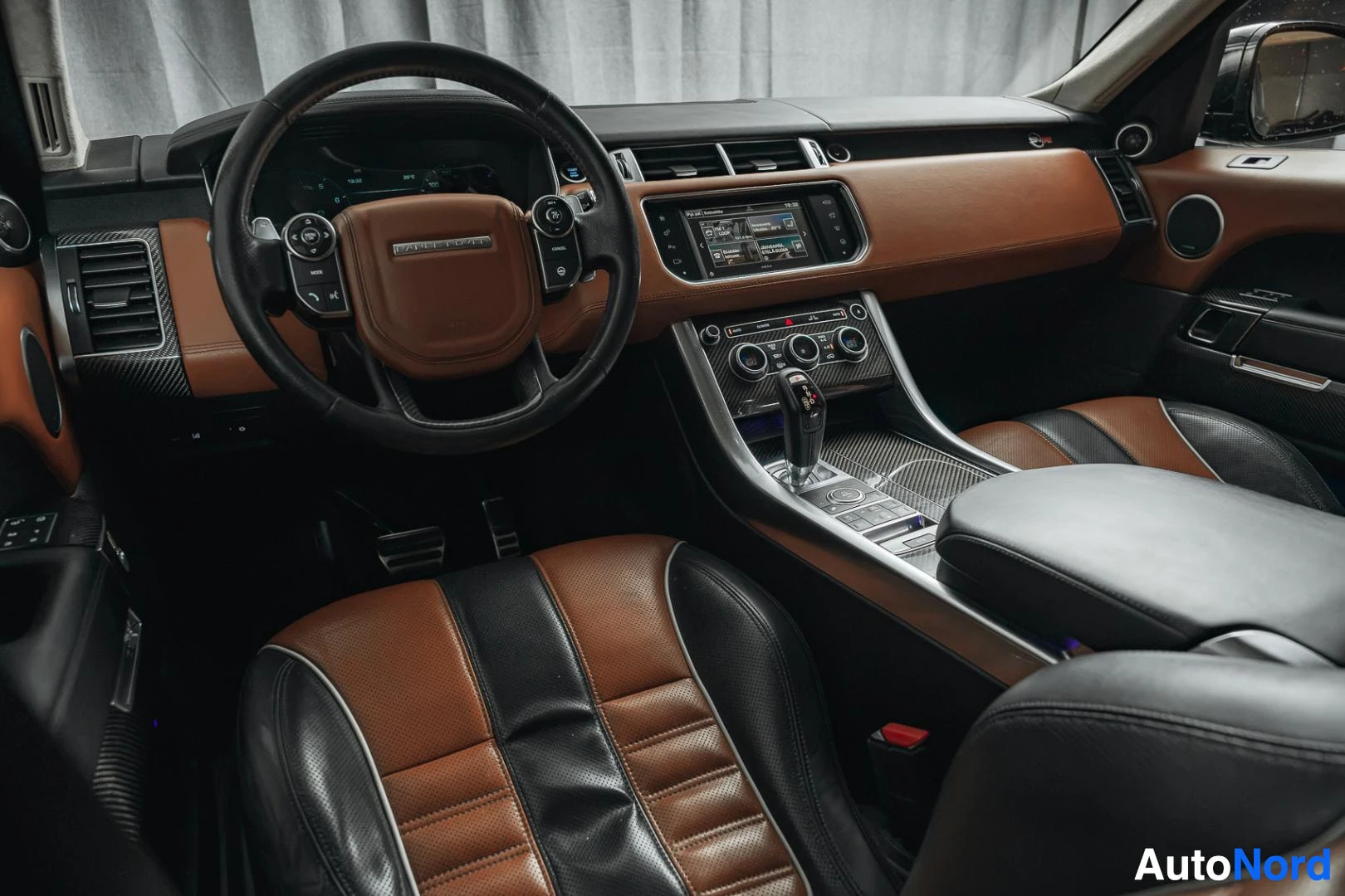 Ohjaamo: Musta Land Rover Range Rover Sport, kojelauta kuljettajan puolelta, ohjauspyörä ja ruskea nahkaverhoilu