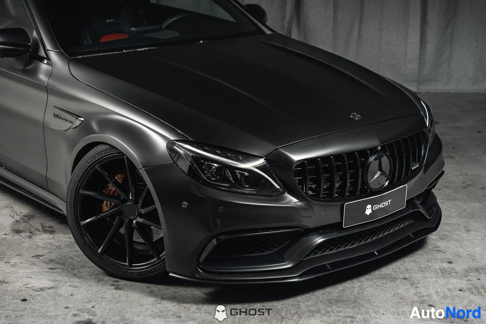 Etuviisto, nokka oikealle: Mattamusta Mercedes-Benz C 63 AMG coupé, lähikuva keulasta ja mustasta etuvanteesta