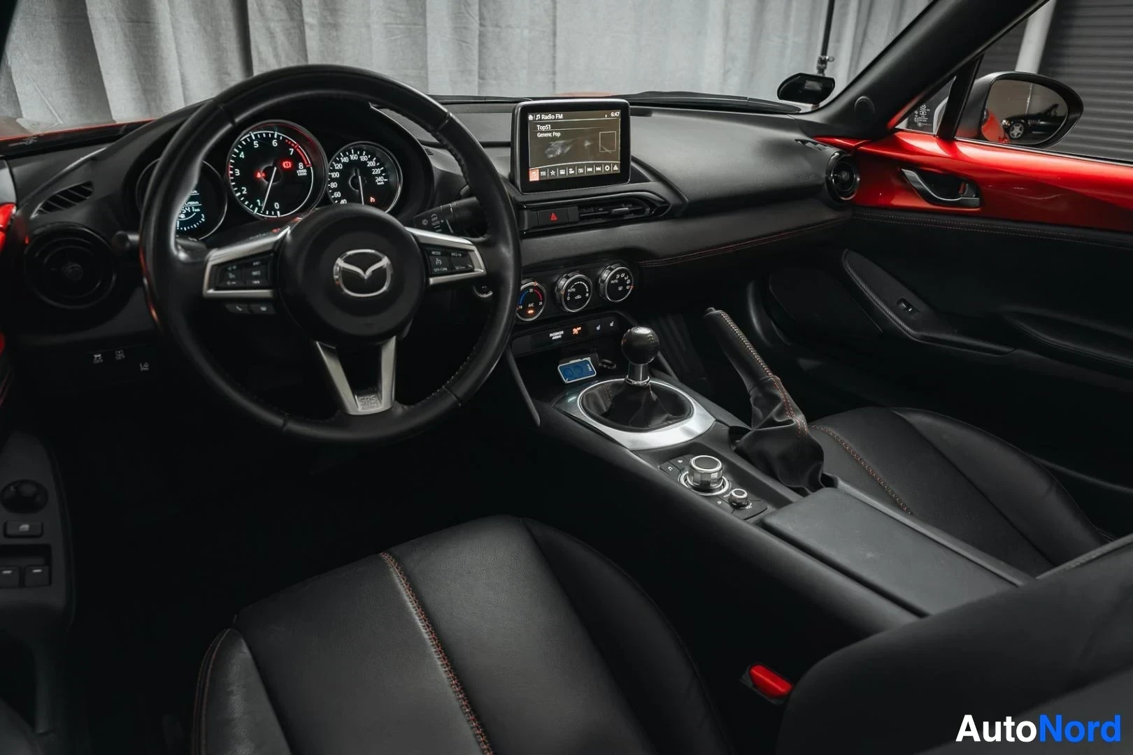 Ohjaamo: Punainen Mazda MX-5, kojelauta kuljettajan puolelta, ohjauspyörä ja mustat nahkaistuimet