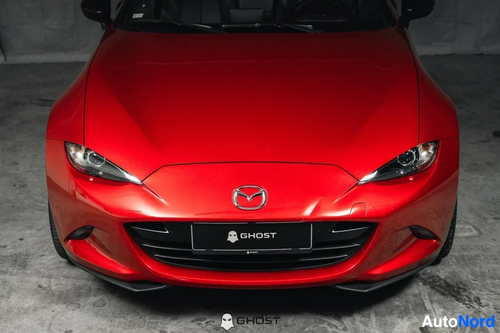 Edestä: Punainen Mazda MX-5, lähikuva keulasta, ajovalot ja Mazda-logo