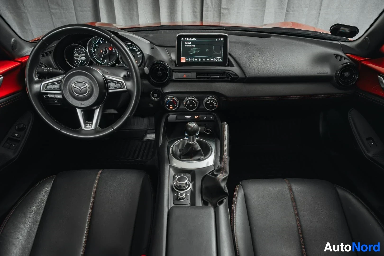 Ohjaamo: Punainen Mazda MX-5, kojelauta, ohjauspyörä, keskinäyttö ja mustat nahkaistuimet