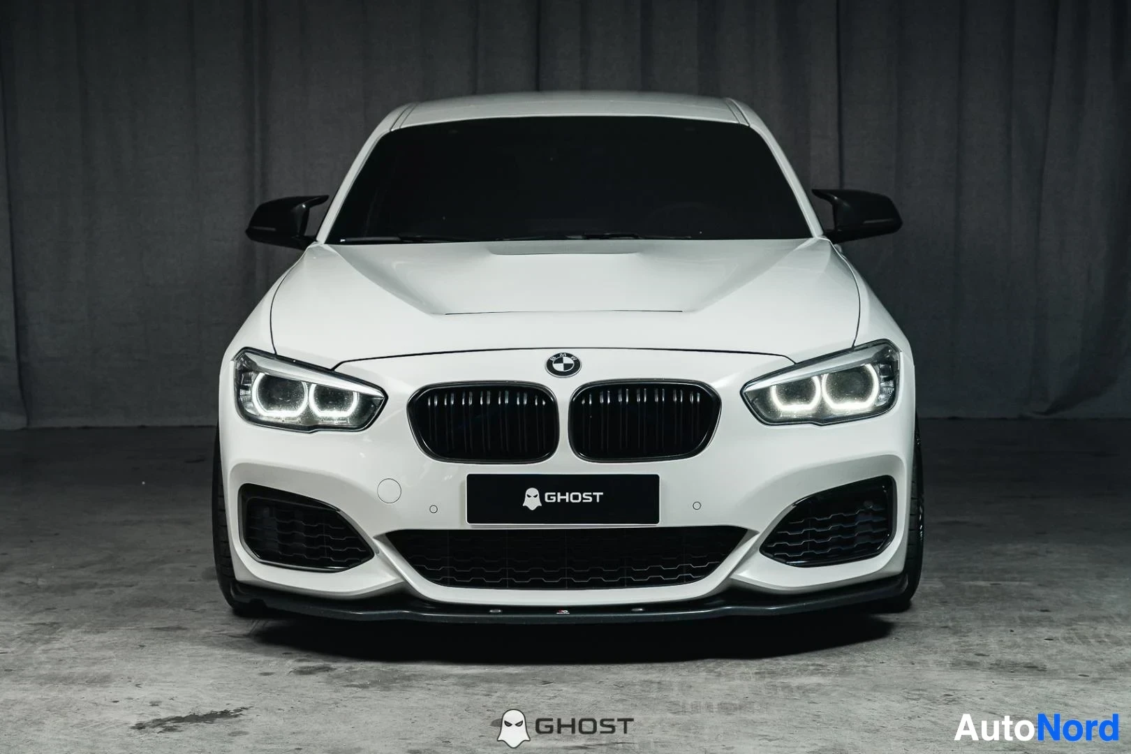 Edestä: Valkoinen BMW M140i F20 xDrive, koko ajoneuvo näkyvissä, LED-ajovalot ja M-Sport-etupuskuri, studiotausta