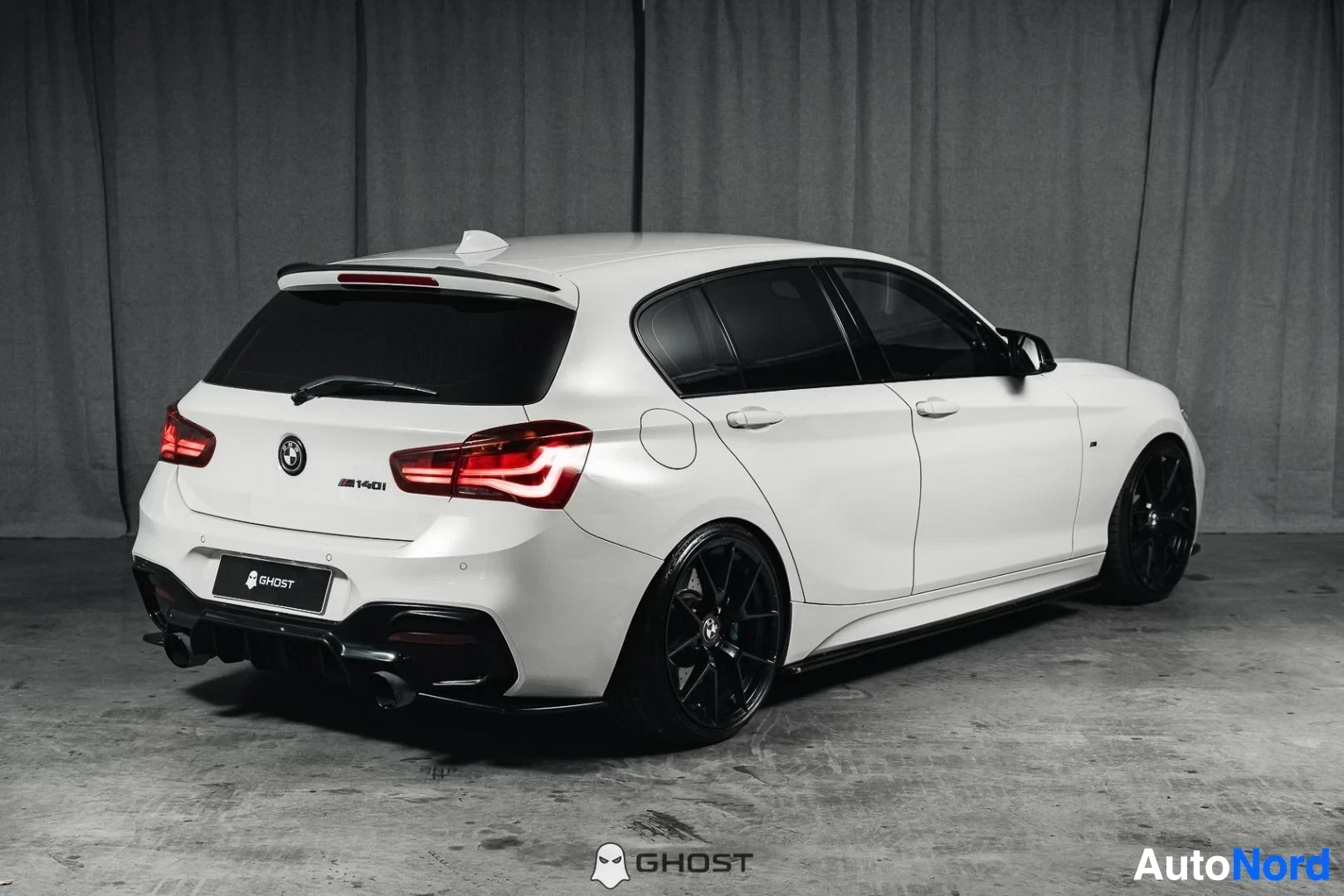 Takaviisto: Valkoinen BMW M140i F20 xDrive, koko ajoneuvo näkyvissä, takaosa ja kylki, studiotausta