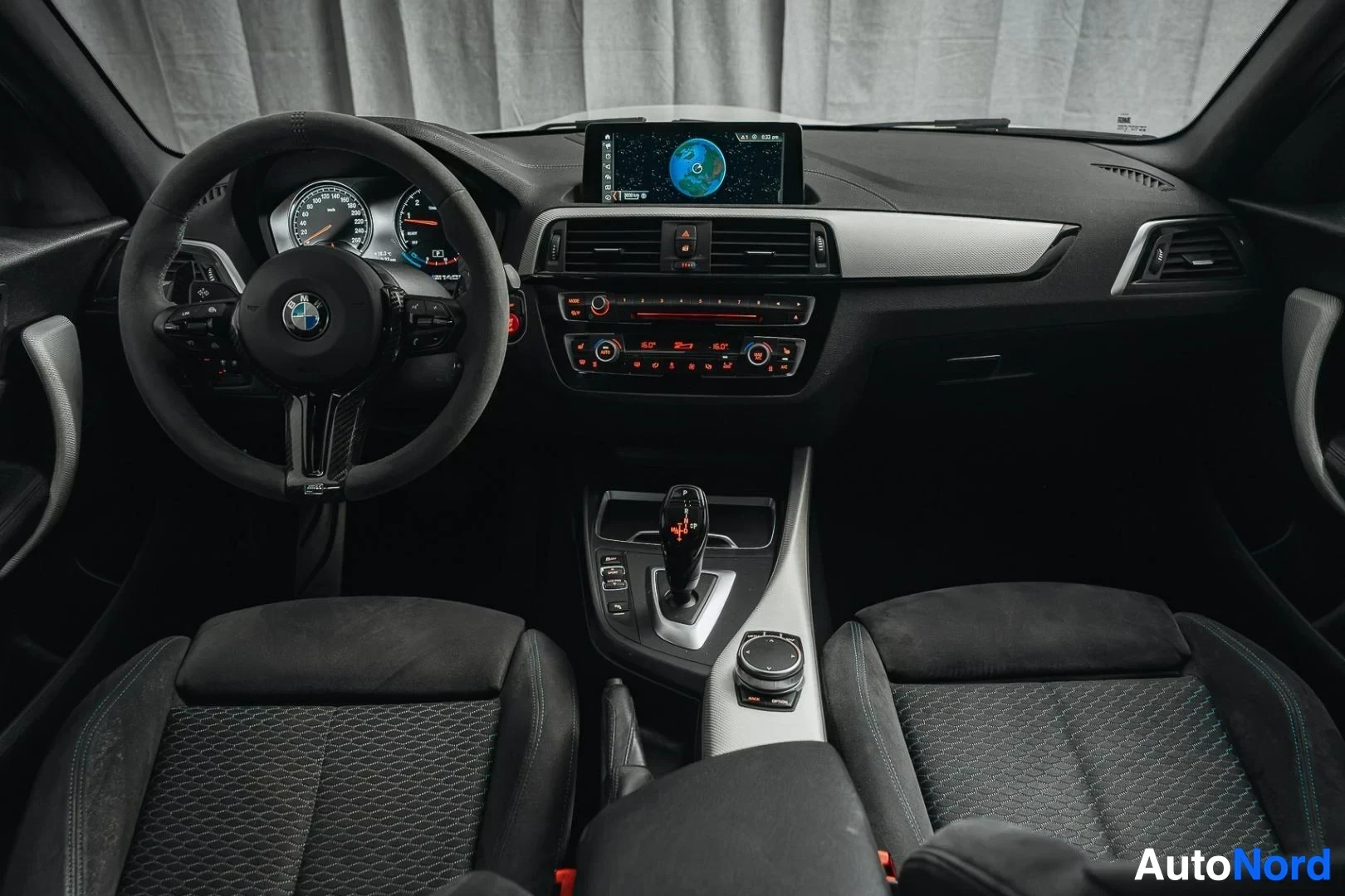 Ohjaamo: Valkoinen BMW M140i F20 xDrive, kojelauta, keskinäyttö ja etuistuimet takaa kuvattuna, tumma verhoilu