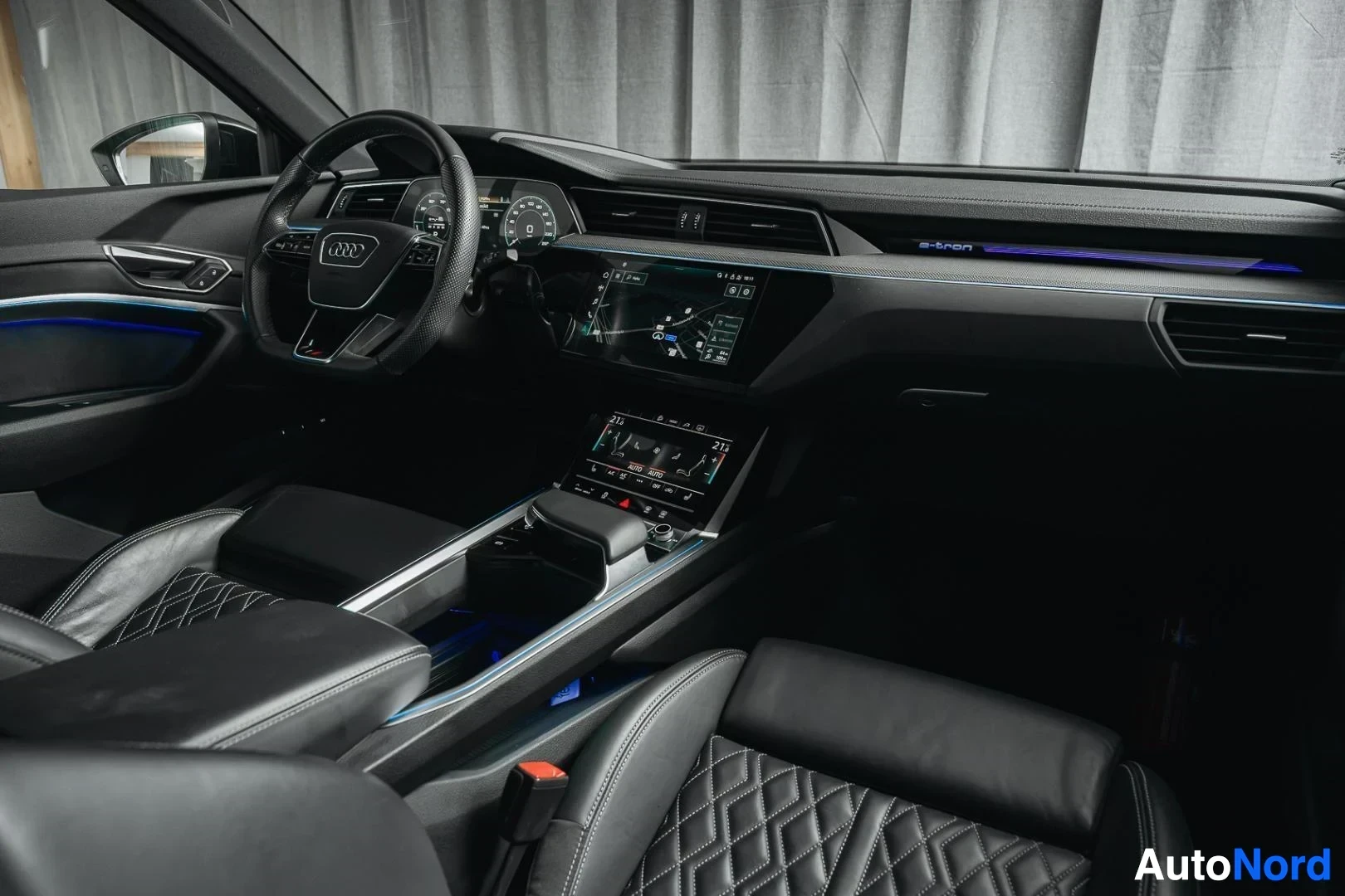 Ohjaamo: Tummanvihreä Audi Q8 e-tron, kojelauta ja keskikonsoli kuljettajan puolelta, tunnelmavalaistus