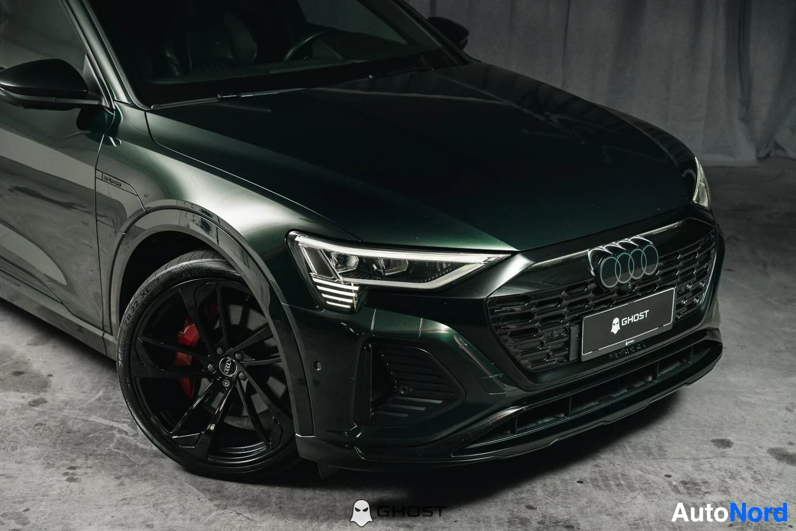 Etuviisto, nokka oikealle: Tummanvihreä Audi Q8 e-tron Sportback, lähikuva keulasta ja etupyörästä, mustat vanteet