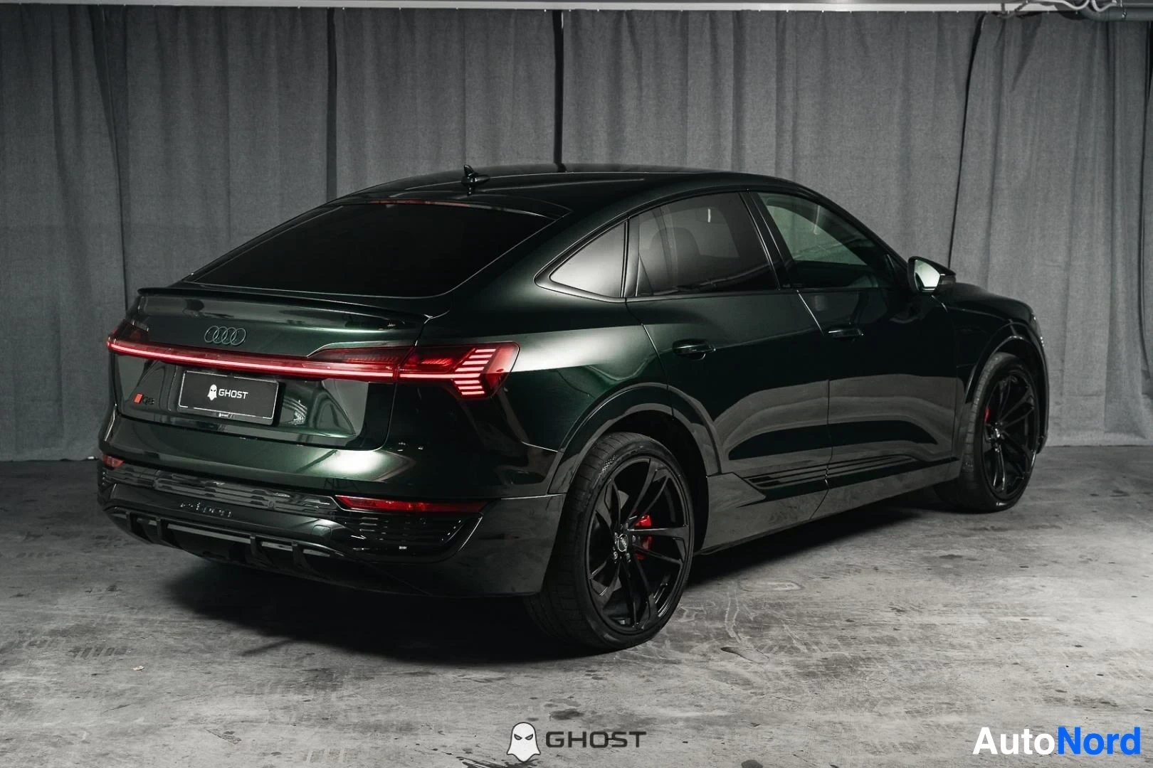 Takaviisto: Tummanvihreä Audi Q8 e-tron Sportback, koko ajoneuvo näkyvissä, LED-takavalopalkki, studiotausta