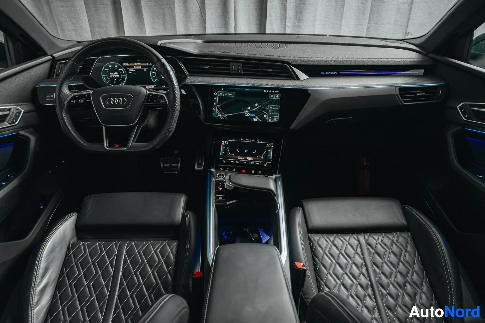 Ohjaamo: Tummanvihreä Audi Q8 e-tron, ohjauspyörä, keskikonsoli ja tikatut nahkaistuimet takaa kuvattuna