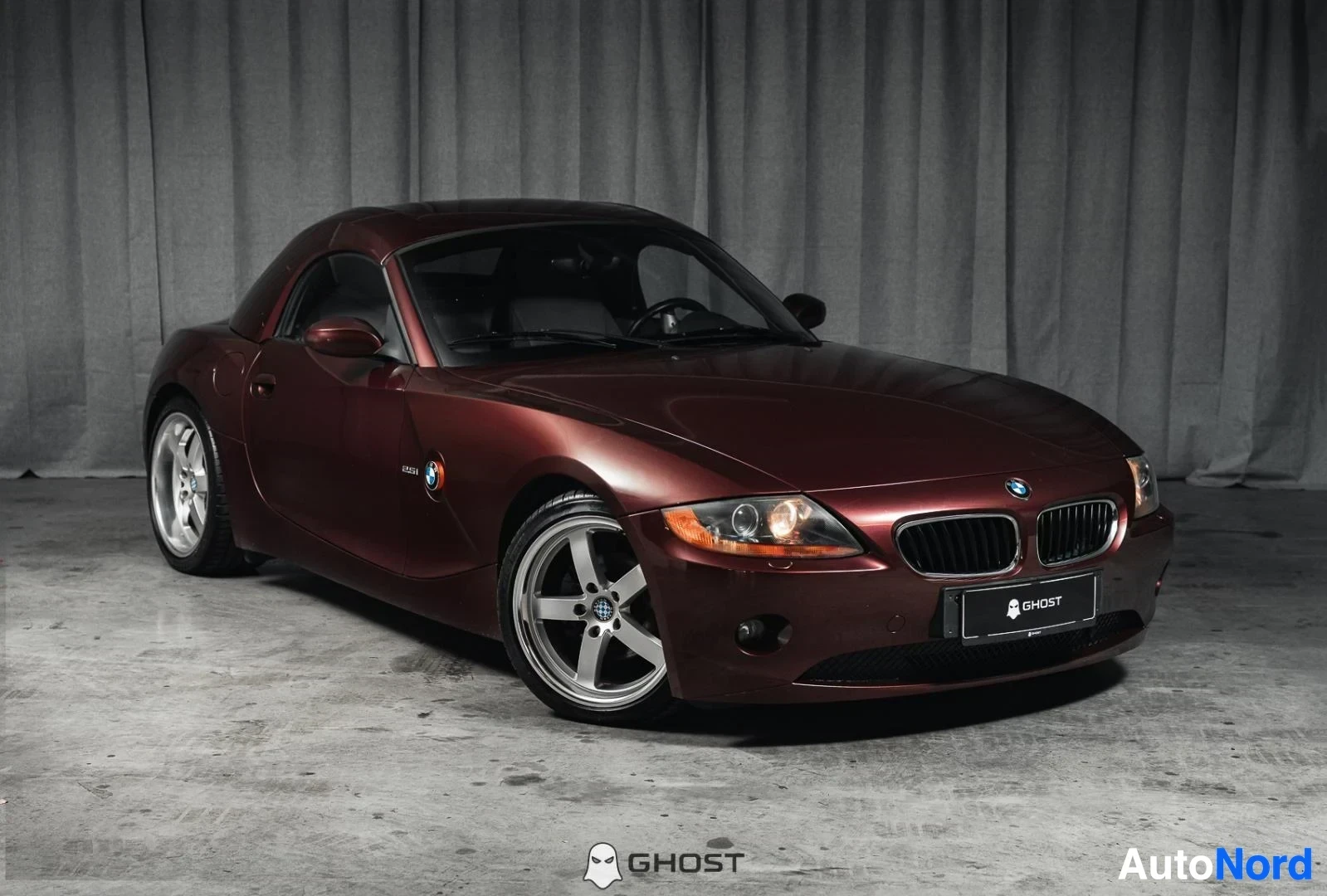 Etuviisto, nokka oikealle: Tummanpunainen BMW Z4 E85 Roadster, koko ajoneuvo näkyvissä, kovakatto paikallaan, hopeanväriset vanteet, studiotausta