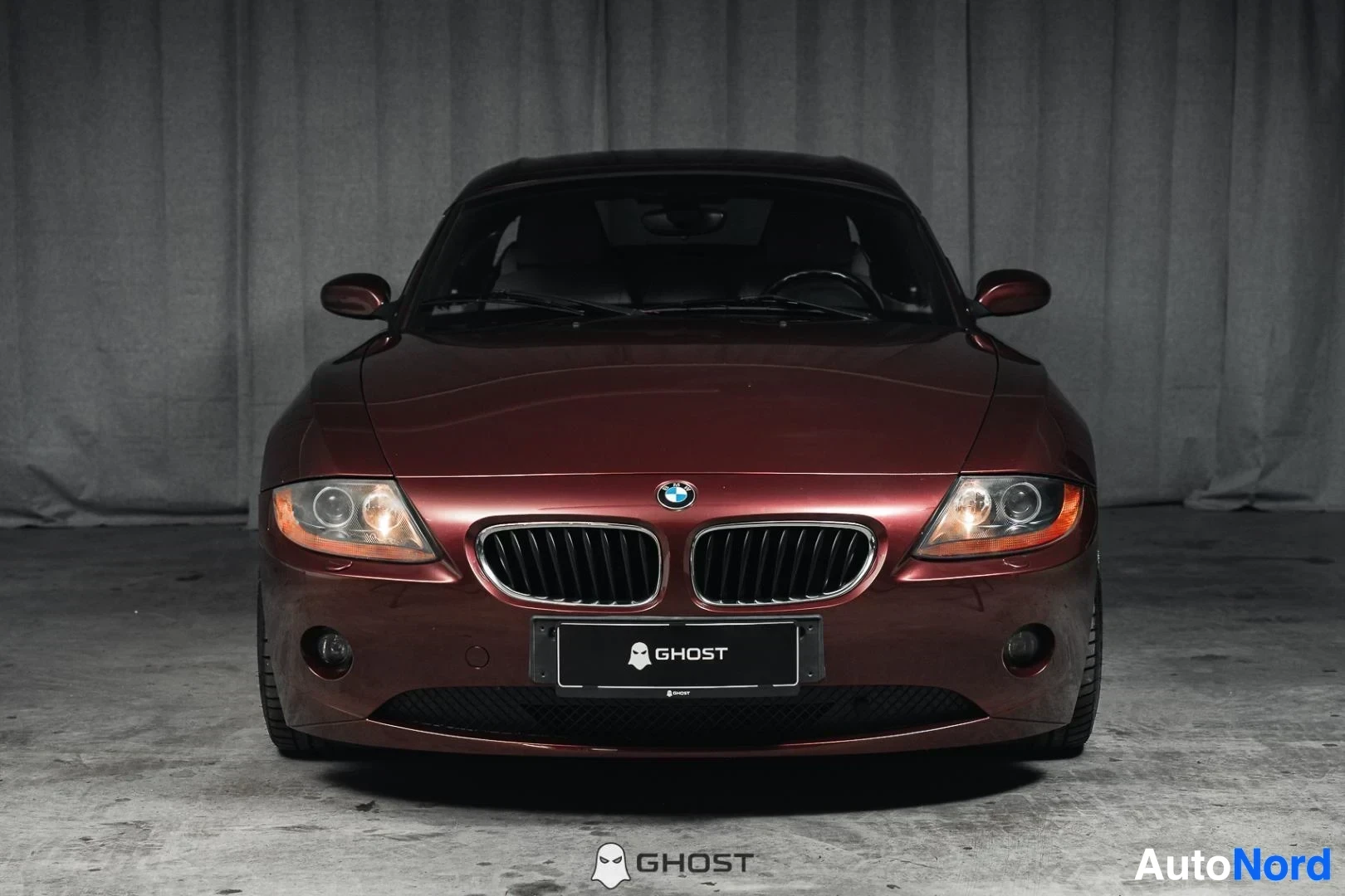 Edestä: Tummanpunainen BMW Z4 E85 Roadster, koko ajoneuvo näkyvissä, keula ja ajovalot, studiotausta