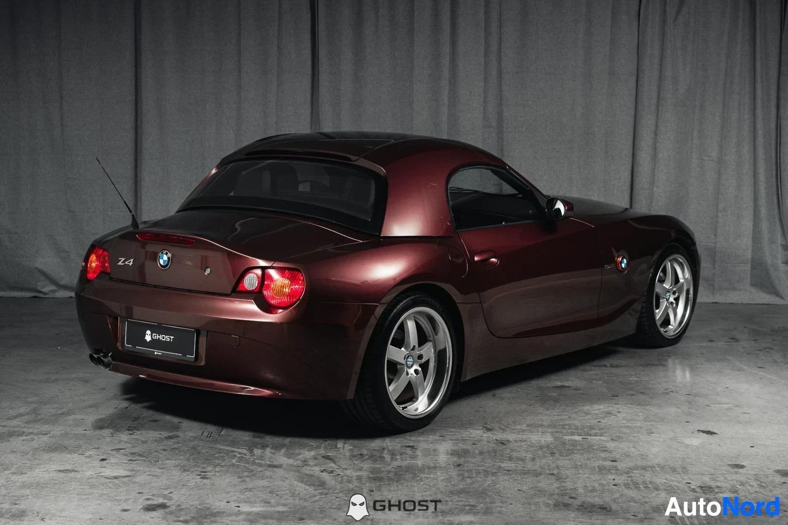 Takaviisto: Tummanpunainen BMW Z4 E85 Roadster, koko ajoneuvo näkyvissä, takaosa ja kylki, kovakatto paikallaan, studiotausta