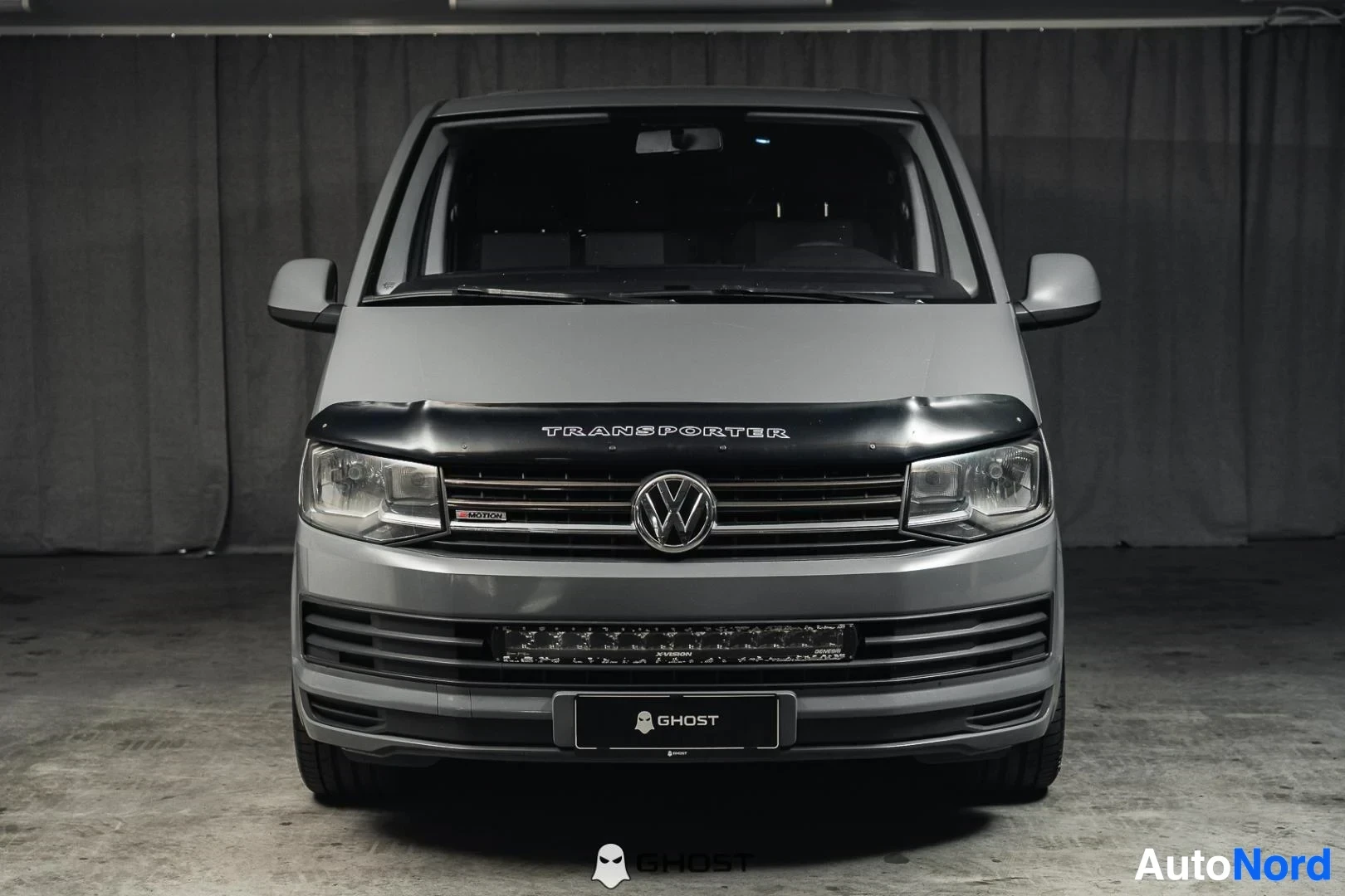 Edestä: Harmaa Volkswagen Transporter, koko ajoneuvo näkyvissä, musta konepellin suoja, studiotausta