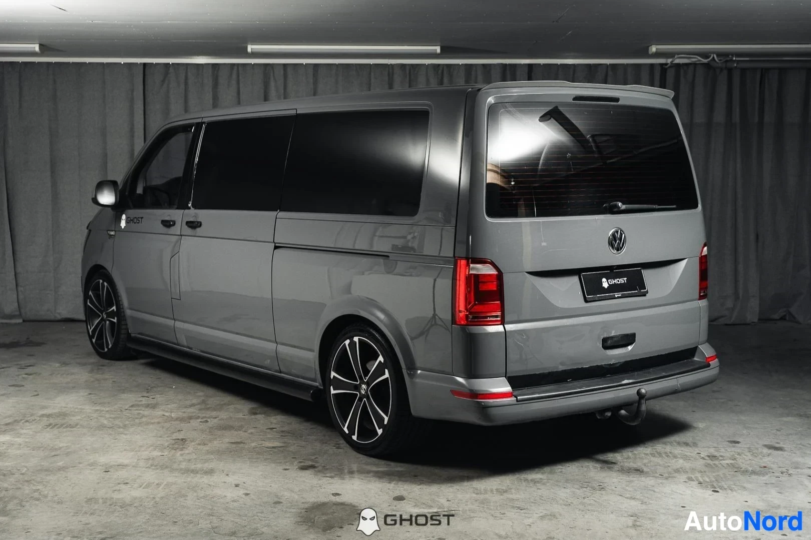 Takaviisto: Harmaa Volkswagen Transporter, koko ajoneuvo näkyvissä, tummat vanteet, studiotausta
